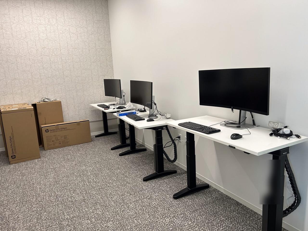 Real workstation setup photo with desks, monitors and endpoint staging in an office rollout area