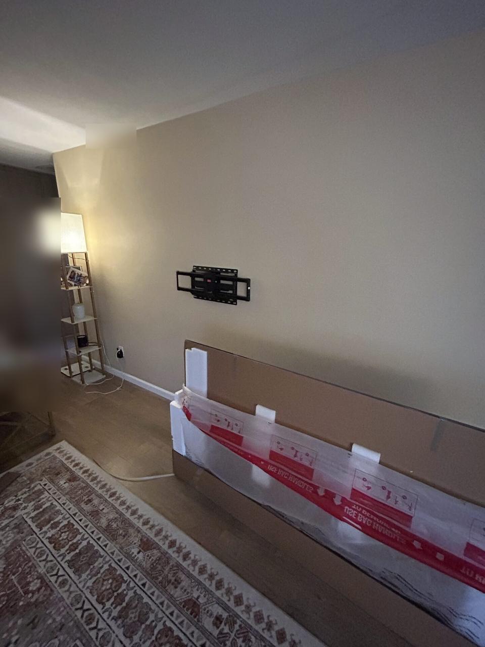 TV wall prepared with mounting bracket location and boxed display ready for installation